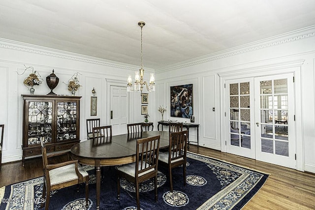 dining space with hardwood / wood-style floors, crown molding, french doors, and an inviting chandelier