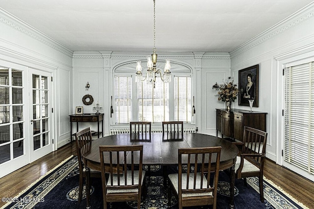 dining space with dark wood-type flooring, french doors, crown molding, and a chandelier