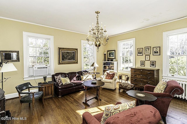 living room with dark wood-type flooring, crown molding, and an inviting chandelier