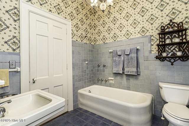 bathroom with toilet, tile patterned flooring, tile walls, and a tub to relax in