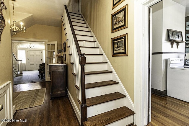 stairway with vaulted ceiling, an inviting chandelier, washer / dryer, and hardwood / wood-style flooring