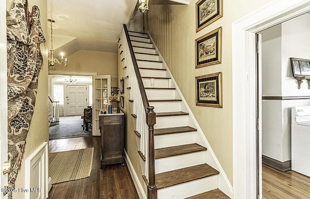 stairway featuring lofted ceiling, wood-type flooring, and an inviting chandelier