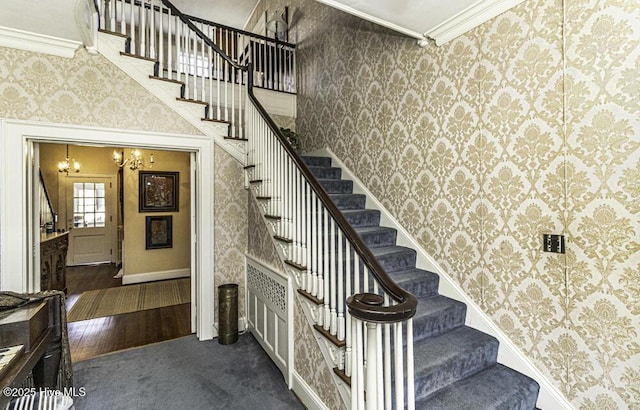 staircase with hardwood / wood-style flooring, crown molding, and a notable chandelier