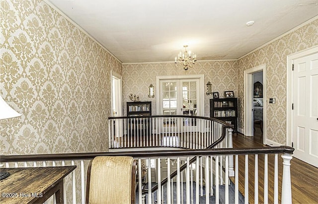 staircase featuring french doors, an inviting chandelier, ornamental molding, and hardwood / wood-style floors