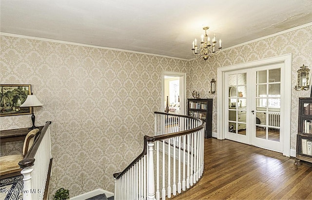 corridor with french doors, dark hardwood / wood-style floors, crown molding, and a notable chandelier