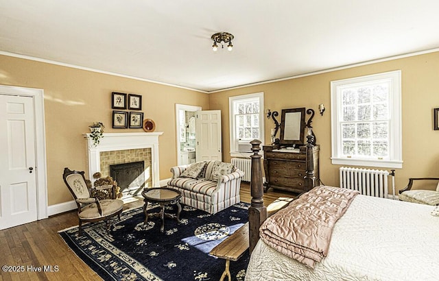 bedroom with dark wood-type flooring, crown molding, a tile fireplace, and radiator heating unit