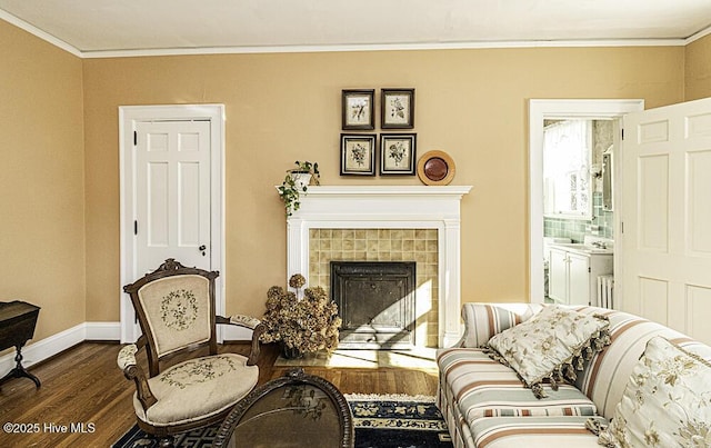 sitting room featuring hardwood / wood-style floors, crown molding, and a tiled fireplace