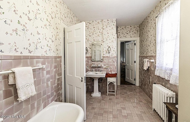 bathroom with radiator, tile walls, sink, and a bath