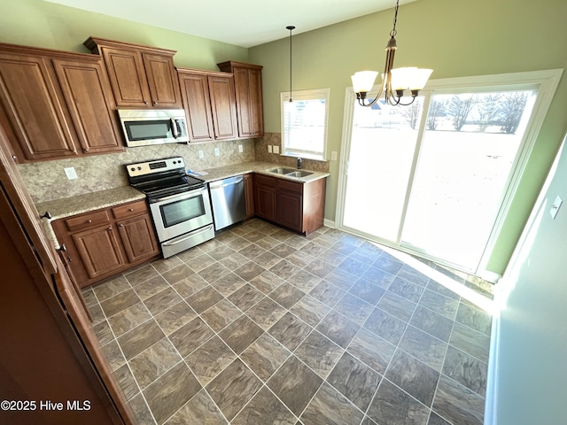 kitchen with sink, hanging light fixtures, tasteful backsplash, a chandelier, and appliances with stainless steel finishes