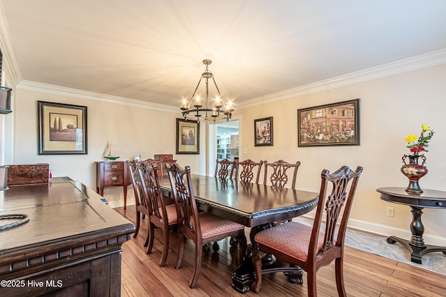 dining room with light hardwood / wood-style flooring, an inviting chandelier, and ornamental molding