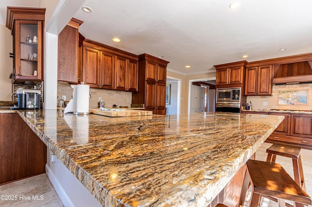 kitchen with tasteful backsplash, custom exhaust hood, a breakfast bar, stainless steel appliances, and stone countertops