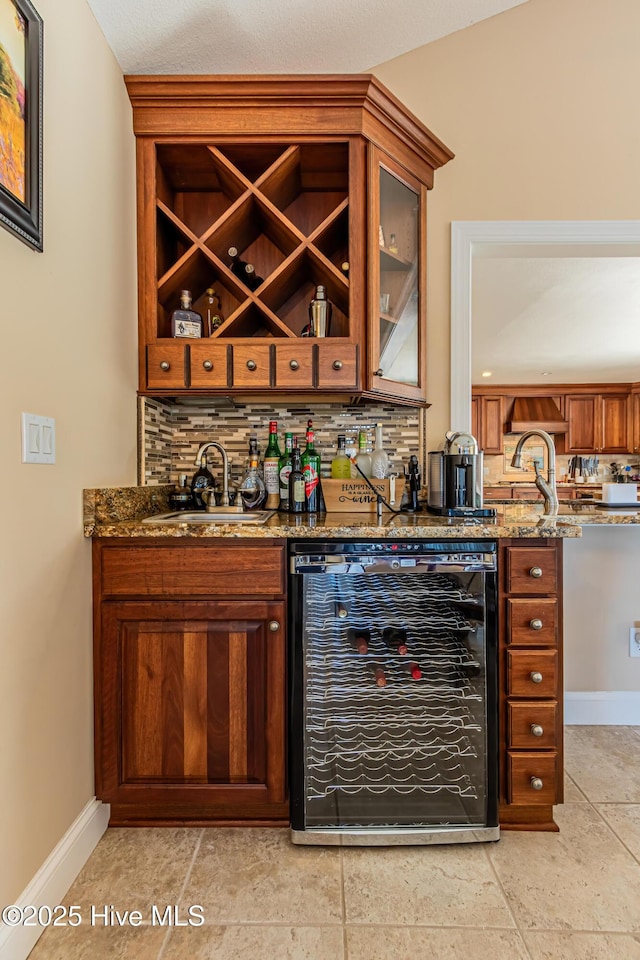 bar featuring backsplash, dark stone countertops, sink, and beverage cooler