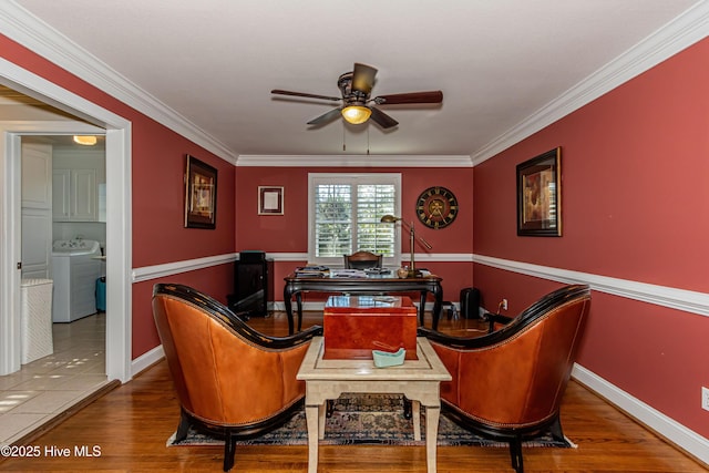 living area featuring hardwood / wood-style floors, washing machine and dryer, ceiling fan, and ornamental molding