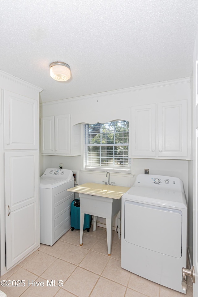 clothes washing area featuring cabinets, light tile patterned floors, washer and dryer, and ornamental molding