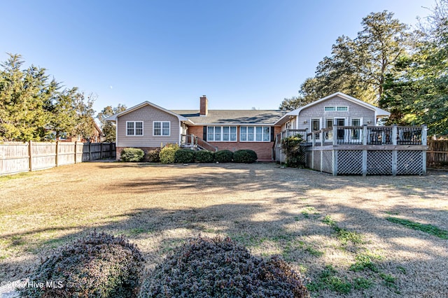 back of house featuring a lawn and a deck