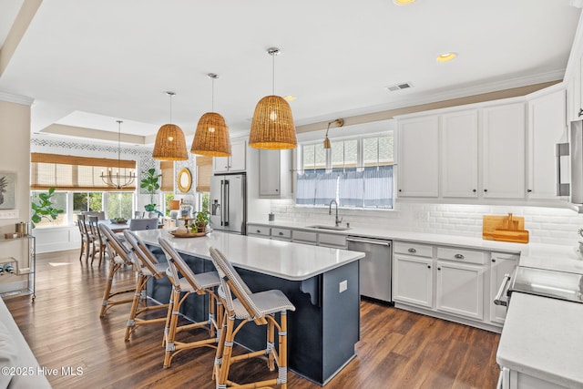 kitchen with a kitchen bar, white cabinetry, a center island, pendant lighting, and stainless steel appliances