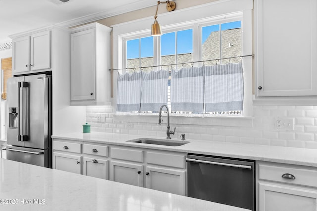 kitchen with sink, hanging light fixtures, appliances with stainless steel finishes, white cabinets, and backsplash