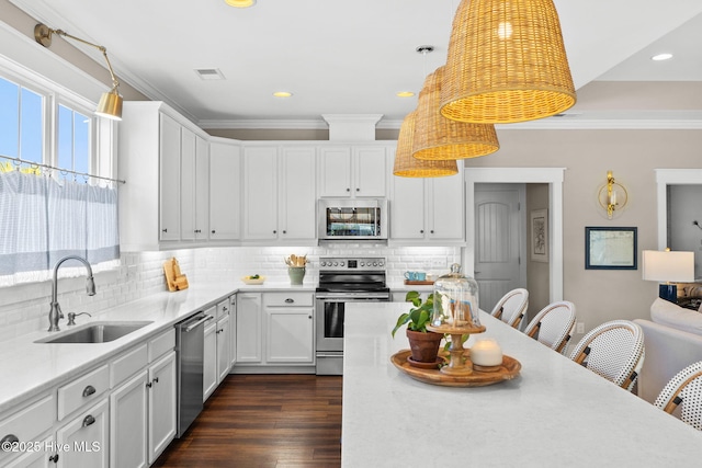 kitchen featuring appliances with stainless steel finishes, sink, hanging light fixtures, and white cabinets