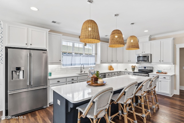 kitchen featuring pendant lighting, crown molding, white cabinetry, stainless steel appliances, and a center island