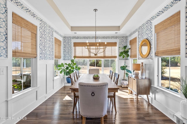 dining space featuring dark hardwood / wood-style flooring, a tray ceiling, plenty of natural light, and an inviting chandelier