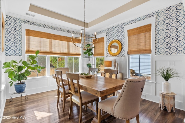 dining space featuring crown molding, dark hardwood / wood-style floors, a raised ceiling, and an inviting chandelier