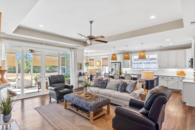 living room with dark hardwood / wood-style flooring, a tray ceiling, french doors, and ceiling fan