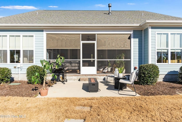 rear view of property with a fire pit, a sunroom, and a patio