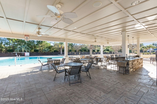 view of patio / terrace with exterior bar, a community pool, and ceiling fan