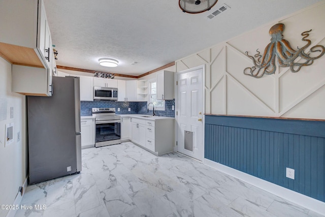 kitchen with sink, a textured ceiling, appliances with stainless steel finishes, white cabinets, and backsplash