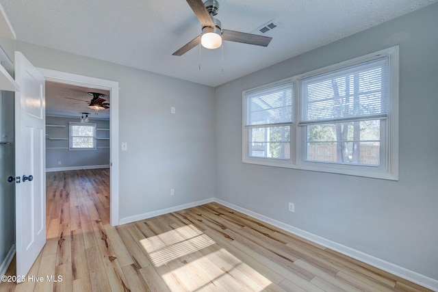 spare room featuring ceiling fan, light hardwood / wood-style floors, and a textured ceiling