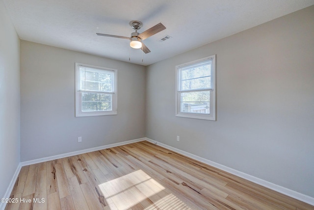 empty room featuring plenty of natural light, ceiling fan, and light wood-type flooring