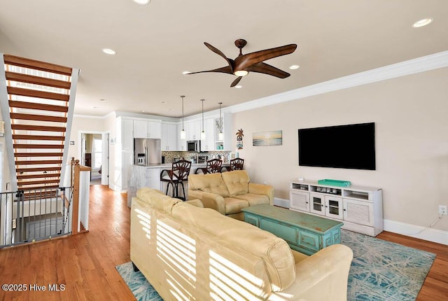 living room featuring ceiling fan, light hardwood / wood-style floors, and ornamental molding