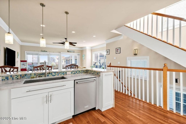 kitchen with dishwasher, white cabinets, sink, light wood-type flooring, and decorative light fixtures