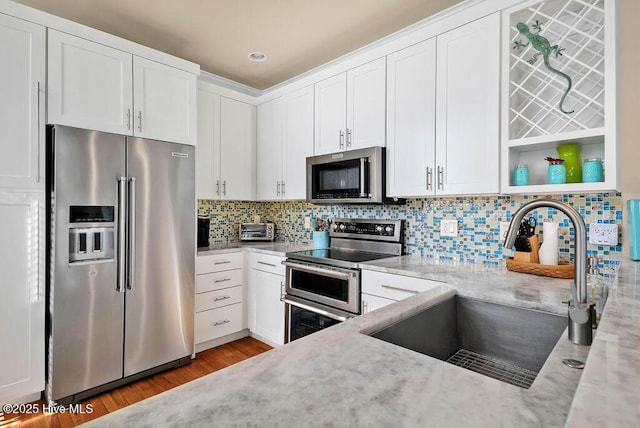 kitchen with light stone countertops, sink, white cabinets, and stainless steel appliances