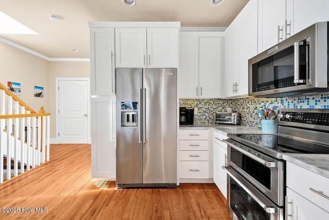 kitchen featuring white cabinets, light hardwood / wood-style flooring, decorative backsplash, appliances with stainless steel finishes, and light stone counters