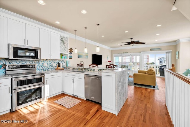 kitchen featuring kitchen peninsula, appliances with stainless steel finishes, ceiling fan, decorative light fixtures, and white cabinetry