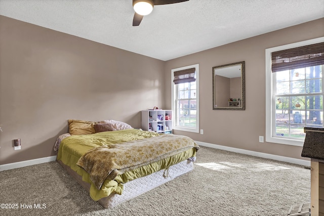 carpeted bedroom featuring ceiling fan, a textured ceiling, and multiple windows