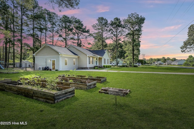 back house at dusk featuring a lawn