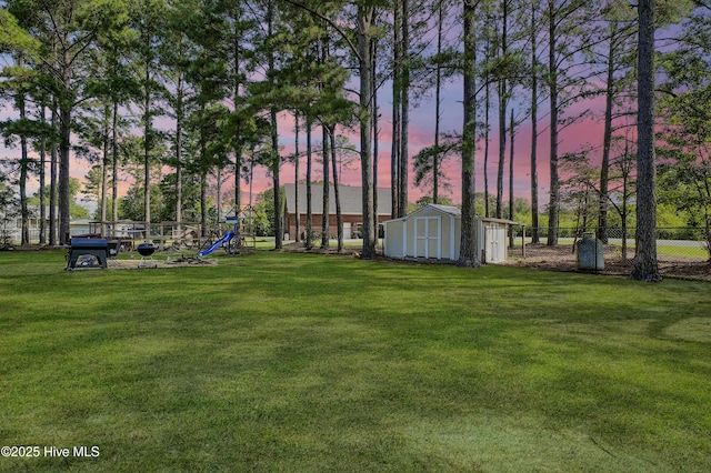 yard at dusk with a playground and a storage unit