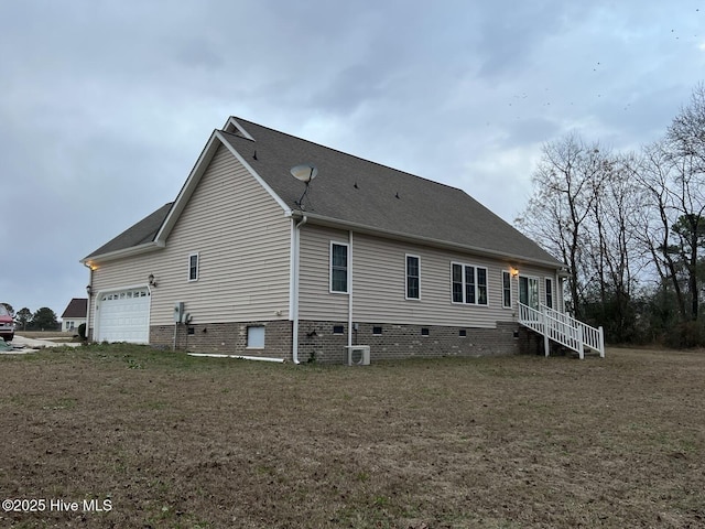 view of side of property featuring a lawn, cooling unit, and a garage