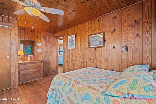 bedroom with wooden walls, dark hardwood / wood-style flooring, ceiling fan, and wooden ceiling