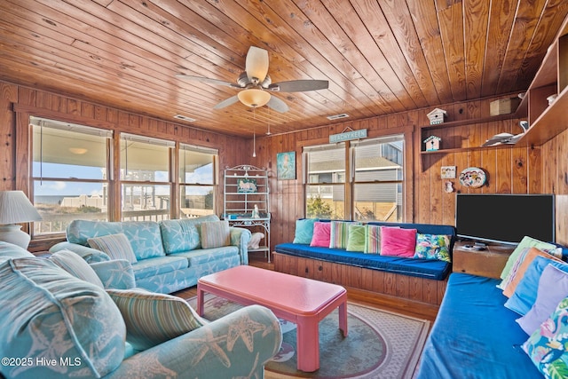 living room featuring wooden walls, ceiling fan, and wood ceiling