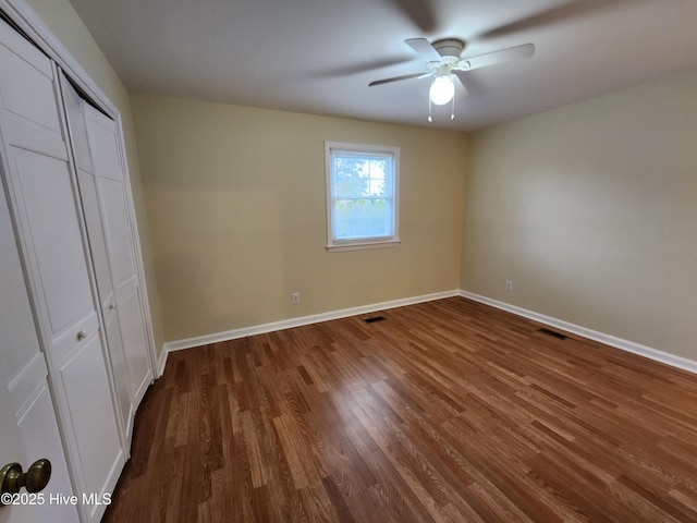 unfurnished bedroom featuring ceiling fan, dark hardwood / wood-style flooring, and a closet