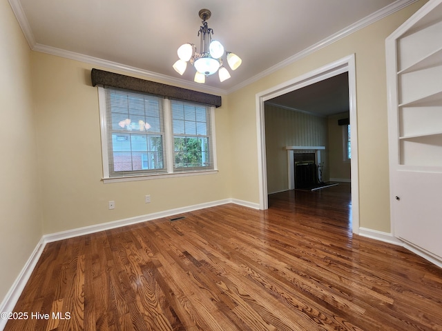 unfurnished dining area featuring a chandelier, built in shelves, dark hardwood / wood-style floors, and crown molding