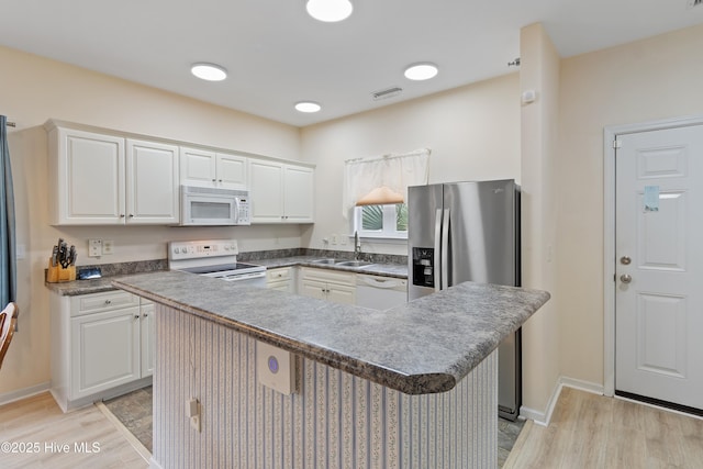 kitchen with sink, white appliances, light hardwood / wood-style flooring, white cabinetry, and a center island