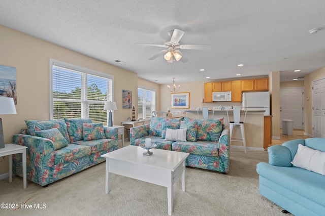 carpeted living room with ceiling fan with notable chandelier and a textured ceiling