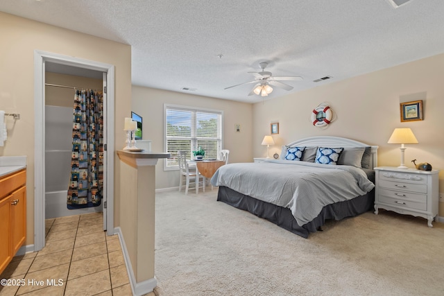 bedroom featuring a spacious closet, ceiling fan, a textured ceiling, and light colored carpet