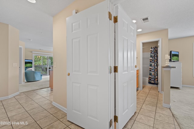 hallway featuring a textured ceiling and light colored carpet