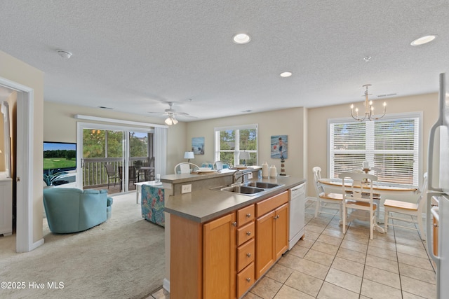 kitchen featuring light carpet, an island with sink, white appliances, hanging light fixtures, and sink