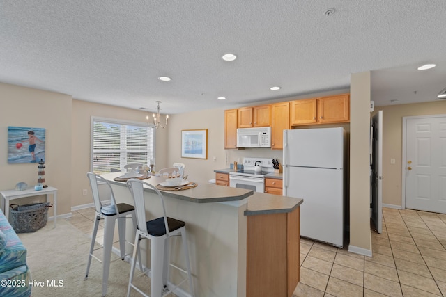 kitchen featuring white appliances, a center island, hanging light fixtures, a notable chandelier, and light tile patterned flooring